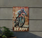 a painting of a man riding a motorcycle on a rusty sign