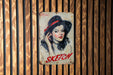 a painting of a woman with a hat on a wooden wall