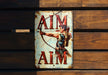 a sign on a wooden wall that says aim aim