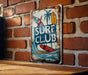 a surf club sign on a brick wall
