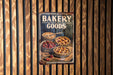 a bakery sign hanging on the side of a wooden wall