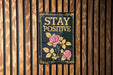 a sign on a wooden wall that says stay positive