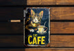 a metal sign with a cat sitting on top of a cup of coffee