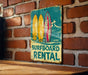 a surfboard rental sign on a brick wall