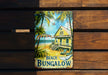 a beach bungalow sign hanging on a wooden wall