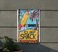 a surf shack sign hanging on the side of a building