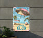 a beach club sign hanging on the side of a building