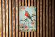 a red bird sitting on top of a sign on a wooden wall