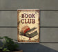 a book club sign hanging on the side of a building