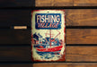 a fishing village sign hanging on a wooden wall