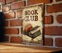 a book club sign hanging on a brick wall