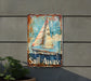 a rusted sail away sign hanging on the side of a building