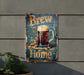 a beer sign hanging on a wall next to a potted plant