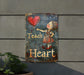 a metal sign with a girl holding a heart