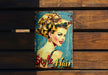 a tin sign with a woman's hair on it