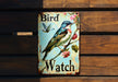 a bird watch sign on a wooden wall