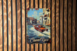 a painting of a boat in a canal on a wooden wall