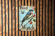 a bird watch sign on a wooden wall