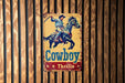a cowboy sign mounted to the side of a wooden wall