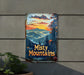a rusty mountain sign hanging from the side of a building