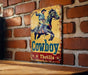a cowboy sign is mounted on a brick wall