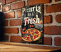 a sign on a brick wall that says pizza and fresh