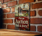 a sign on a brick wall that says farm auction bid and buy