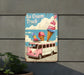 a pink ice cream truck sign hanging on the side of a building