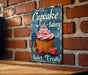 a sign on a brick wall that says cupcake bakery