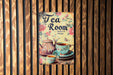 a tea room sign hanging on a wooden wall
