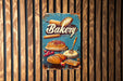 a bakery sign hanging on a wooden wall