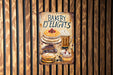 a bakery sign hanging on a wooden wall