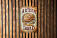 a sign on a wooden wall that says artisan bread