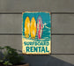a surfboard rental sign hanging on the side of a building