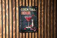 a metal sign on a wooden wall that says cocktail hour