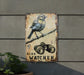 a bird sitting on top of a sign next to a plant