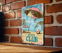 a picture of a beach club sign on a brick wall