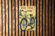 a bicycle trail sign on a wooden wall