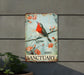 a red bird sitting on top of a sign on a wall