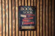 a book nook sign hanging on a wooden wall