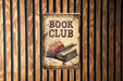 a book club sign hanging on a wooden wall