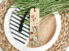 a bookmark sitting on top of a plate next to a plant