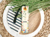 a bookmark sitting on top of a plate next to a plant