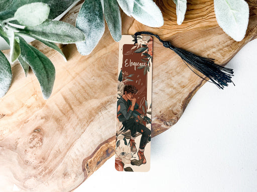 a bookmark sitting on top of a wooden table next to a plant