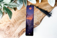 a bookmark sitting on top of a wooden table next to a plant