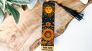 a bookmark with a sun on it sitting on a piece of wood