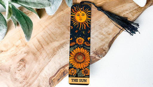 a bookmark with a sun on it sitting on a piece of wood
