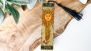 a bookmark with a sun on it sitting on a piece of wood