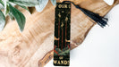 a bookmark with a tassel on top of a piece of wood