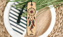 a wooden bookmark with a tassel on top of a plate